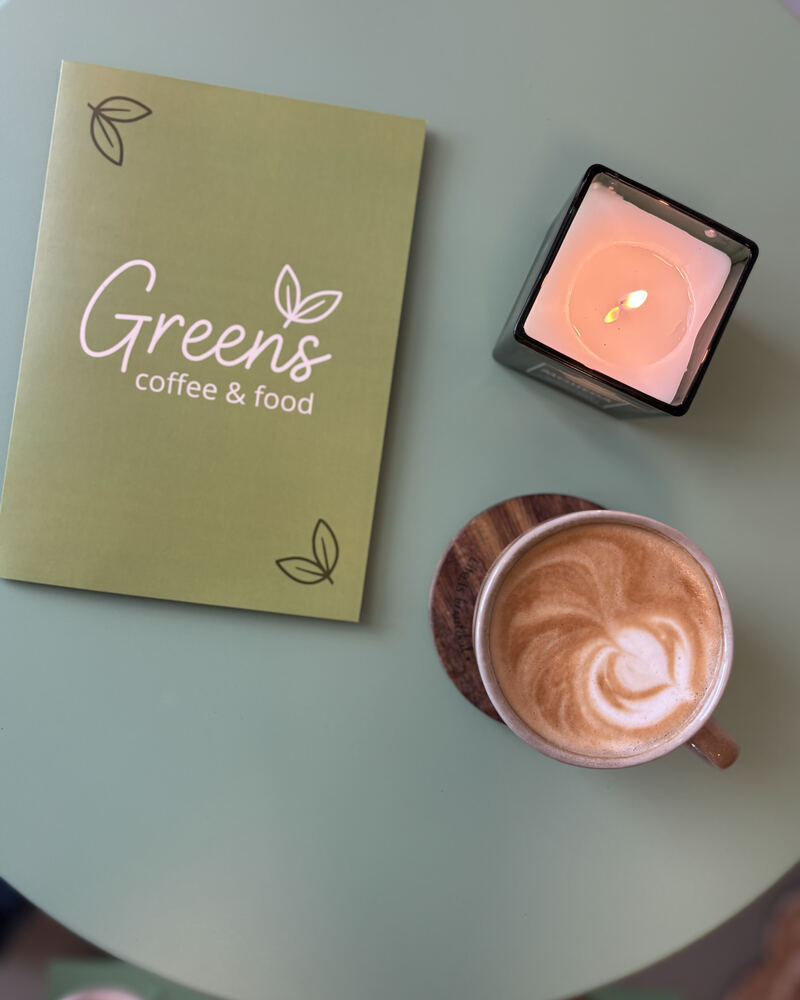 Cappuccino, svíčka a zelené desky s logem Greens